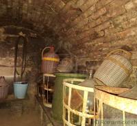 A wine cellar at the cottage with stones and demijohns in Kamenín.
