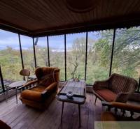 A cottage with a view of nature, comfortable armchairs, and a floor with a wooden decor.