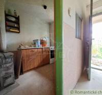 Interior of a cottage with an old stove and furniture on the floor with wooden decor.