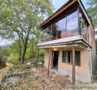 A cottage in Kamenín surrounded by greenery, with a glass terrace and a driveway.