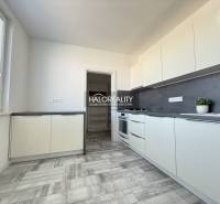 A kitchen in a 2-room apartment with a wooden decor floor and light furniture.