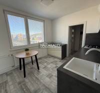 A kitchen in a 2-room apartment with a view, wooden decor flooring, simple furniture.