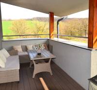 A spacious balcony with rattan furniture and a wooden decor floor in a studio apartment.