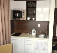 A compact kitchenette in a 2-room apartment with white cabinets and appliances.