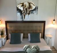 A bedroom with stylish lighting and a picture of an elephant in a 2-room apartment.