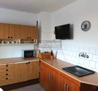 A kitchen in a family house with a wooden kitchen unit, a microwave, and a television on the wall.