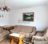 Living room of a family house with a sofa, painting, and dining table.