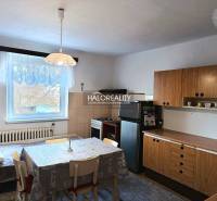 A kitchen in a family house with a dining table and wooden cabinets.