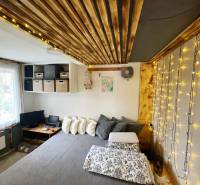 Interior of a family house with string lights, wood-patterned flooring, and a comfortable bed.