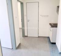 The interior of offices with laminate flooring and white walls, a kitchen unit in the corner.