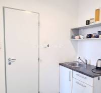 A small office kitchenette with a sink, a shelf, and a kettle.