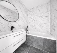 A bathroom with marble tiles, an oval mirror, and a modern sink in a 3-room apartment.