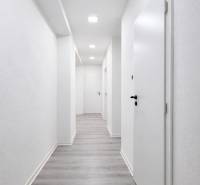 A hallway with white walls and a wooden decor floor in a 3-room apartment.