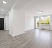 A bright interior of a 3-room apartment with a wooden decor floor and large windows.