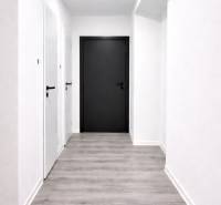 A corridor with light walls and a wooden decor floor in a 3-room apartment.