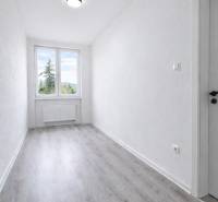 A narrow room with a large window and a floor with wood decor in a 3-room apartment.