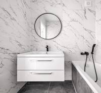 A bathroom in a 3-room apartment with marble tiles, a sink, and a mirror.