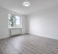A spacious room with a window and a wooden decor floor in a 3-room apartment.