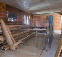 Construction site of a 3-room apartment with unfinished brick walls and wooden beams.