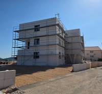 A construction project in the town of Srima, surrounded by scaffolding and a coastal environment.