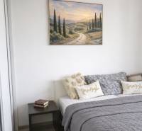 Bedroom in a 2-room apartment with a bed, a painting, and a table on a floor with a wooden decor.