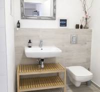 Bathroom with a sink and mirror, simple decoration and light wall tiles in a 2-room apartment.