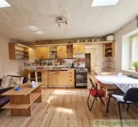 A kitchen in a family house with a wooden decor floor, bright interior, and simple furniture.