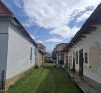 An older family house with a garden and a cloudy sky.