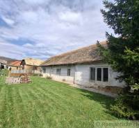 A family house in Ozdín with an original appearance and a grassy yard, surrounded by trees.