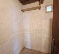 A small room with a concrete floor in a family house, wooden ceiling, simple walls.