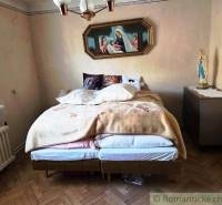 A bedroom in a family house with a bed and religious decoration on the wall.