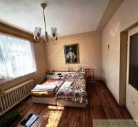 Bedroom in a family house with a bed, chandelier, painting, and floor with wooden decor.