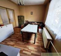 Dining room in a family house with a wooden decor floor and a tiled stove.