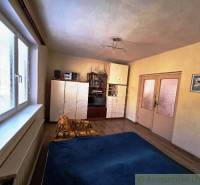 A room with a wooden floor design, a bed, a wardrobe, and a decorative painting in a family house.