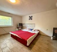A bedroom with a stove, television, and bed, with a wooden decor floor.