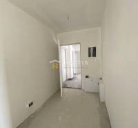 A hallway in a 2-room apartment with white walls, doors, and a floor in a raw state.