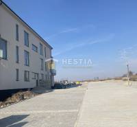 A newly built 3-room apartment in Petrová Ves with a surrounding paved road and clear sky.