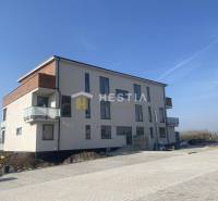 A three-story building with balconies in Petrová Ves on a paved area.