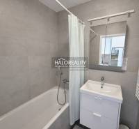 A bathroom with a bathtub, sink, and mirror in a 2-room apartment.