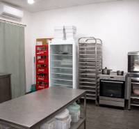 Kitchen gastro spaces with a refrigerator, oven, shelves, and a beverage dispenser.