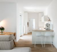 A kitchen with a table, sofa, and wooden decor flooring in a 4-room apartment.