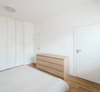 A bedroom in a 4-room apartment with white walls and a wooden decor floor.