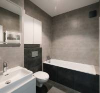 Bathroom with a bathtub, sink, and toilet in a 4-room apartment, stylish gray tiles.