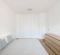 Bright bedroom in a 4-room apartment with a bed, pillows, and a wardrobe, floor with wooden decor.