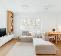 Living room with a sofa, TV, bookshelf, and dining table, floor with wooden decor.