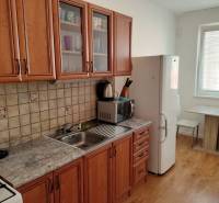 A kitchen in a 3-room apartment with a wooden decor floor and wooden furniture.