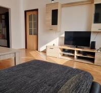 Living room in a 3-room apartment with a wooden decor floor, television, and furniture.