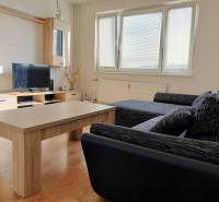 Living room with a sofa, television, and wood-patterned flooring in a 3-room apartment.