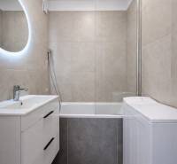 Bathroom in a 2-room apartment with a bathtub and a sink with storage space.