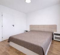 A bedroom in a 2-room apartment with a large bed and a floor with a wooden decor.